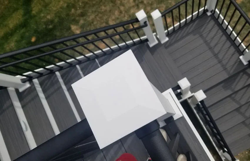 Overhead view of gray composite deck stairs with white posts and black aluminum balusters