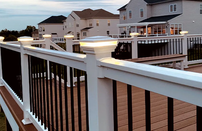 LED post cap lights glowing warmly on composite deck railing posts at twilight