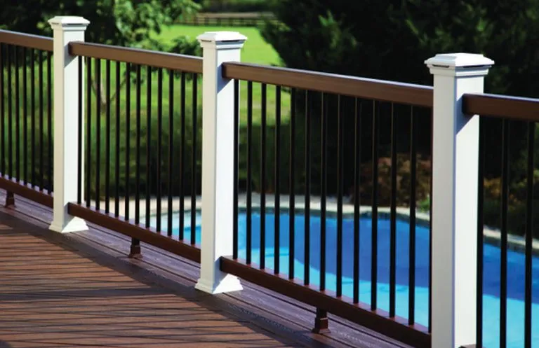 Composite deck railing with white posts and black balusters surrounding pool deck area